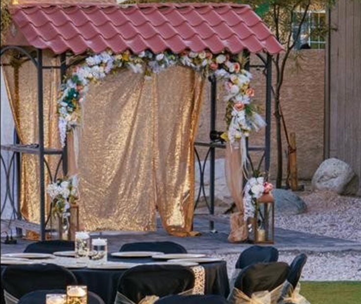 Arco floral dorado y una mesa montada en una recepción al aire libre en Las Vegas