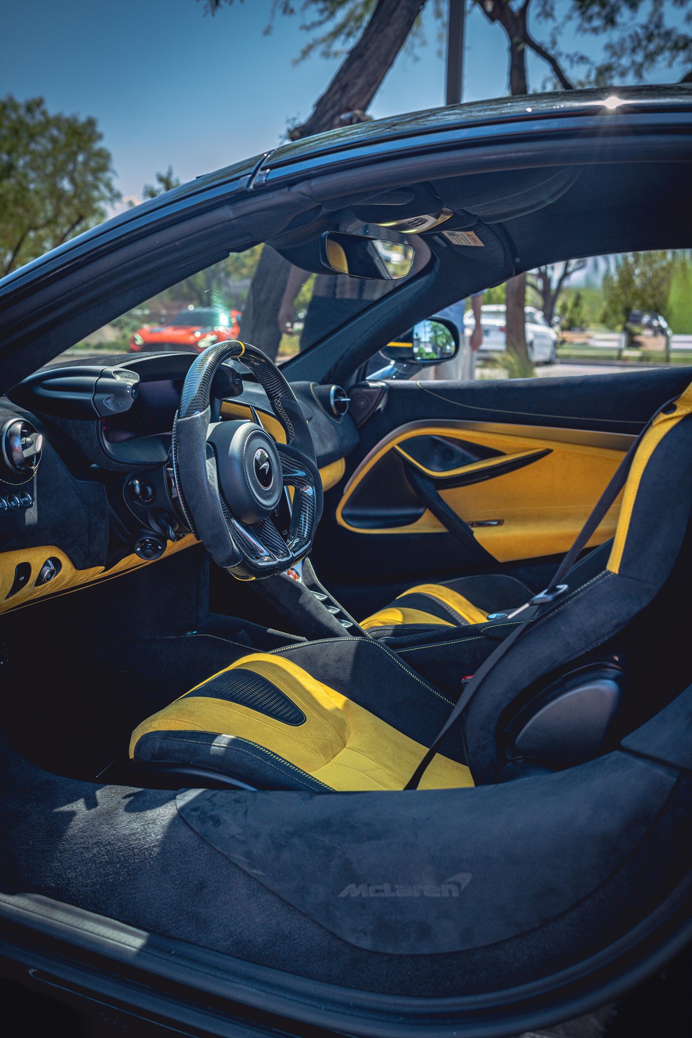 Detalle del interior de un McLaren con asientos de piel amarilla y fibra de carbono