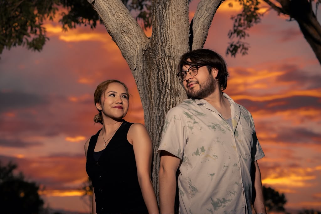 Pareja fotografiada contra un cielo de atardecer encendido