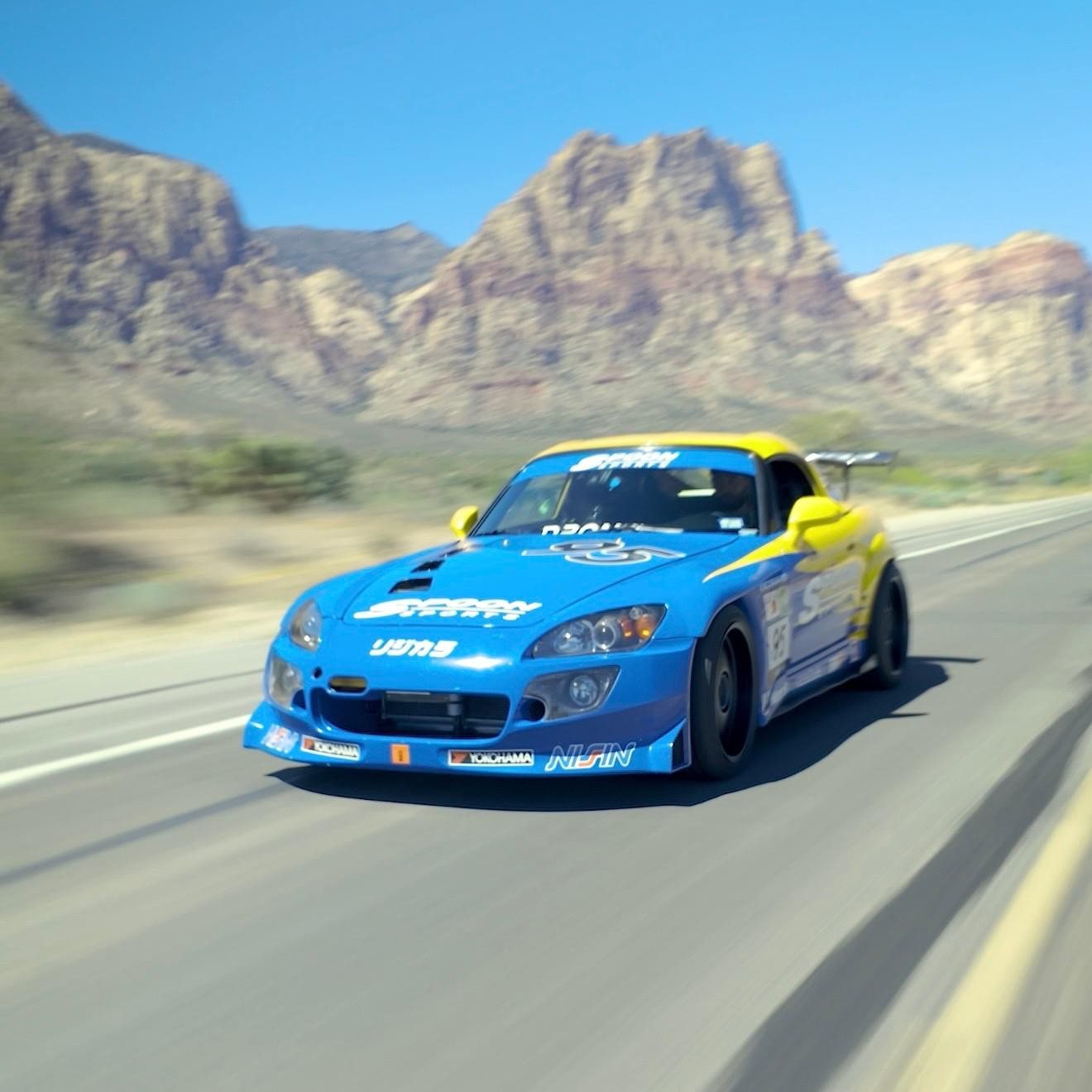 Honda S2000 azul fotografiado en movimiento en una carretera de Red Rock